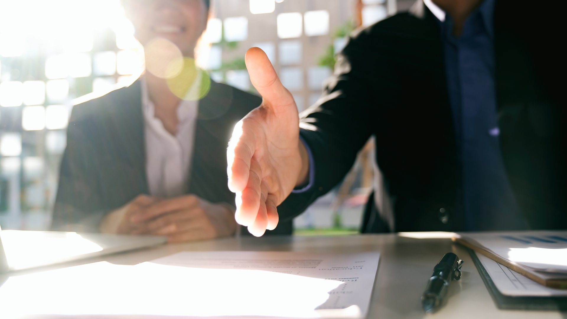 Person sitting at a desk with an outstretched hand