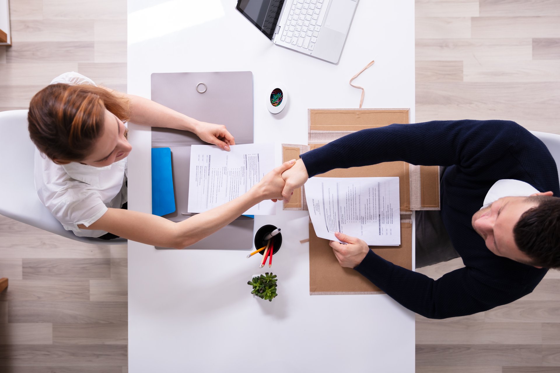 Two people sitting at a desk shaking hands