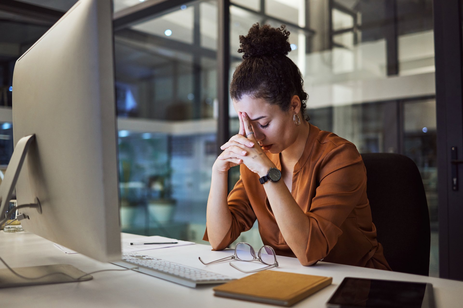 Woman sitting at a desk with her head in her hands